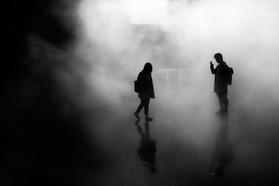 Silhouette man and woman on road in foggy weather