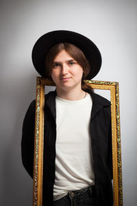 Portrait of young woman standing against wall