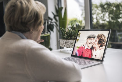 Senior woman on video call with friends through laptop at home