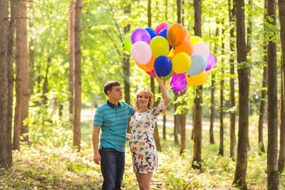 Rear view of two people holding balloons