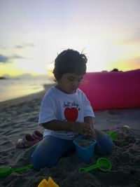 Girl playing with toys at beach during sunset