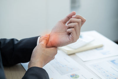 Midsection of man holding paper at table