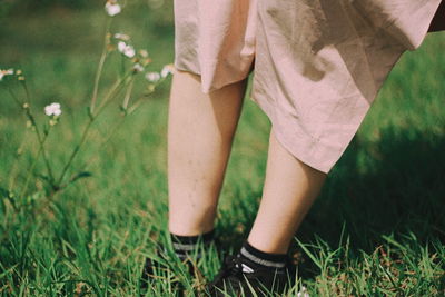 Low section of woman standing on field