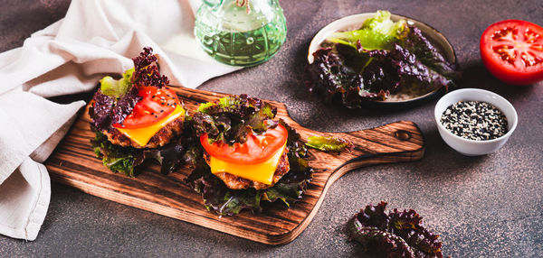 Keto burgers on lettuce leaves from cutlet, tomatoes and cheese on a board web banner