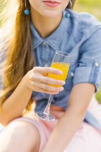 Glass of orange juice in the hand of a young woman person