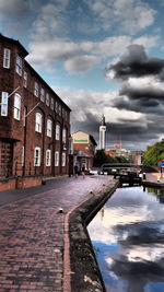 Canal by buildings against sky in city