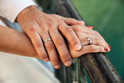 Cropped image of couple holding hands on railing