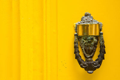 Decorative bronze door handle on a yellow painted door. malta