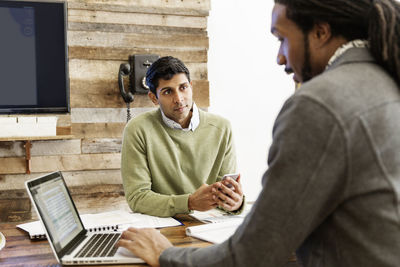 Businessman using laptop while working with colleague at office