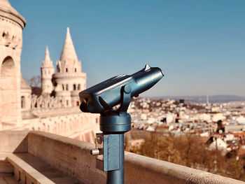 Close-up of coin-operated binoculars against buildings in city