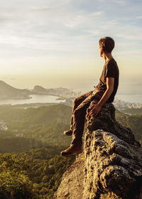 Woman sitting on rock looking at view