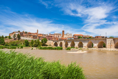 Arch bridge over river against cloudy sky