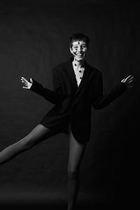 Portrait of smiling young woman standing against black background