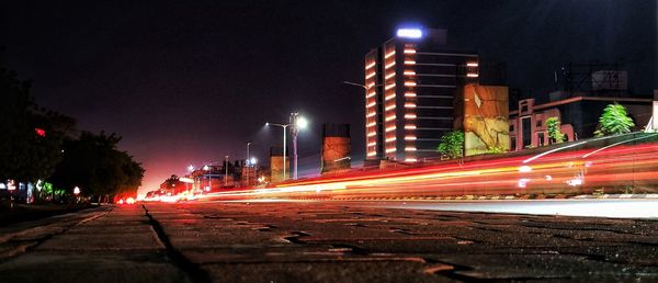 Light trails on road amidst buildings in city at night