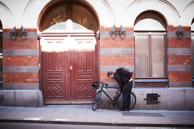 Full length of businessman with bicycle on sidewalk at city