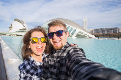 Portrait of happy friends against water against sky