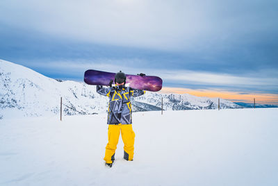 Snowboarder holding a snowboard on the top of the pyrenees mountains, andorra