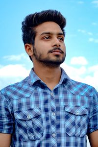 Portrait of man standing against blue sky