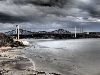 Bridge over river against cloudy sky