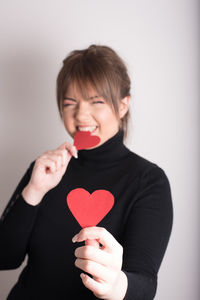 Close-up of woman holding heart shape over white background
