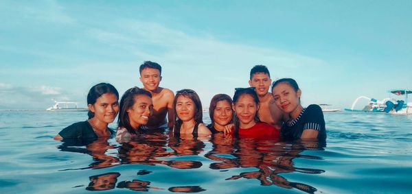 Portrait of people swimming in water against sky