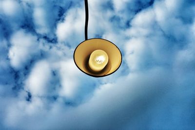 Low angle view of light bulb against cloudy sky