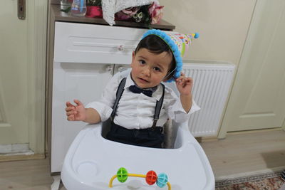 Portrait of baby boy sitting high chair at home