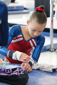 Gymnast girl preparing to complete on bars, putting her grips on.