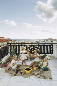 Mother and daughters planting flowers on roof terrace together