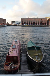 Boats moored in sea by city against sky