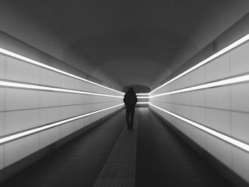 Rear view of person walking in tunnel