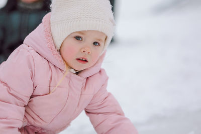 Little girl in pink walks outdoors on winter snowy day