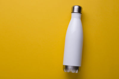 Close-up of white bottle against yellow background