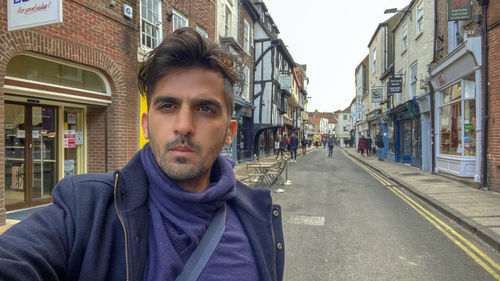 Portrait of young man standing on street in city