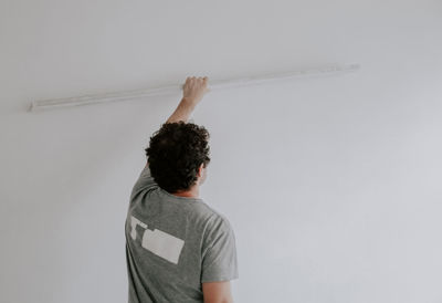 Caucasian plasterer man checks the evenness of the walls after puttying.