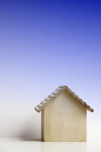 Close-up of model home on table against blue background