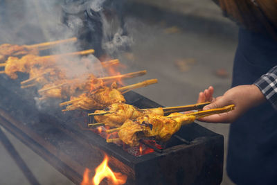 Midsection of woman preparing food on barbecue grill