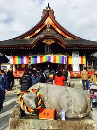 People outside temple against sky in city