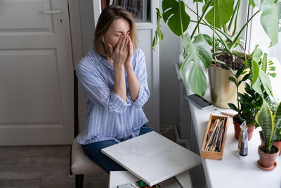 Young woman using phone while sitting on table