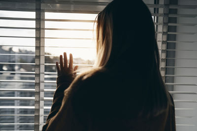 Rear view of woman looking through window