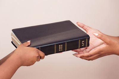 Close-up of hand holding camera over white background