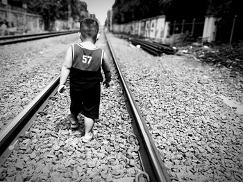 Rear view of man walking on railroad track