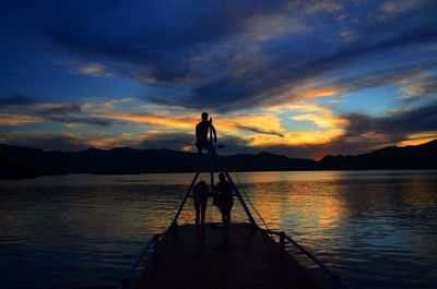 Silhouette man standing by sea against sky during sunset