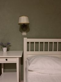 Electric lamp on bed against wall at home