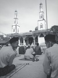 People in front of building against sky in city