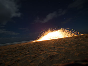 Illuminated beach against sky at night