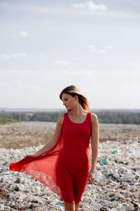 Young woman walking on garbage against sky