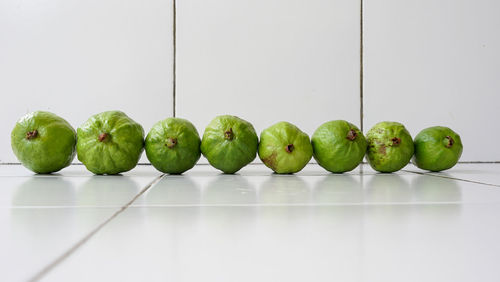 Close-up of green fruits in container against white background