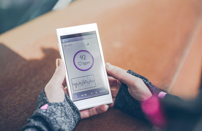 Mid adult woman using heatr rate monitor app on smart phone