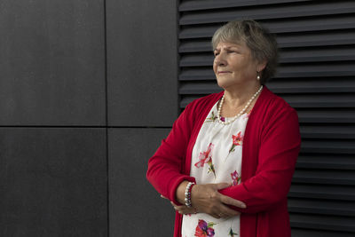 Closeup real senior old 70s pensioner, dark wall on background. portrait of kind relaxed elderly